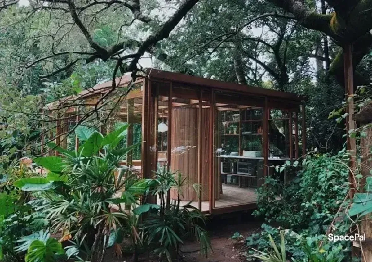 Pabellón de madera y vidrio entre árboles