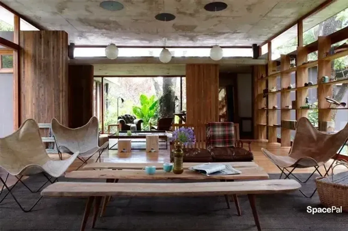 Estar amplio con sillas BKF y biblioteca de madera
